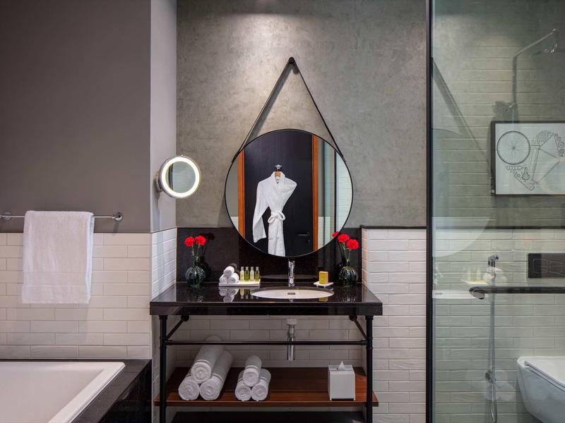 Modern bathroom setup with round mirror, sink, and towels in a hotel room.