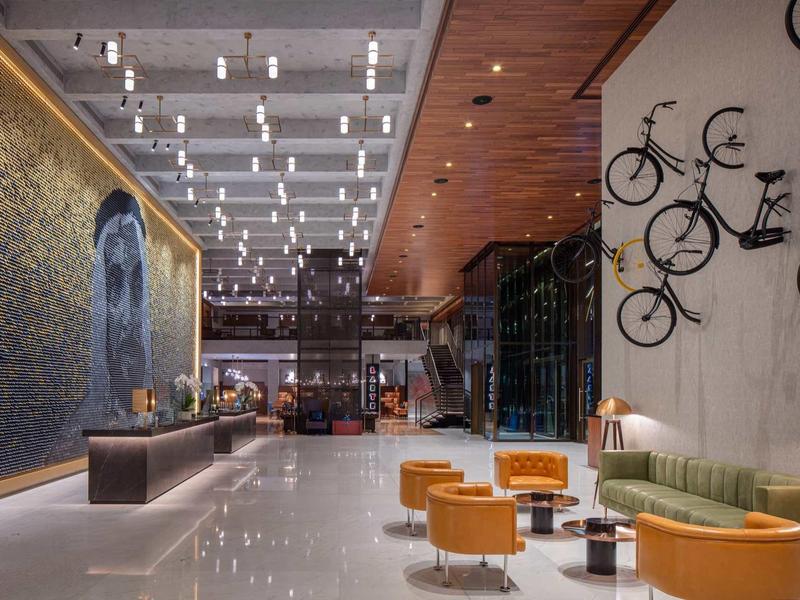 Modern hotel lobby with seating area, bright furniture, and wall-mounted bicycles.