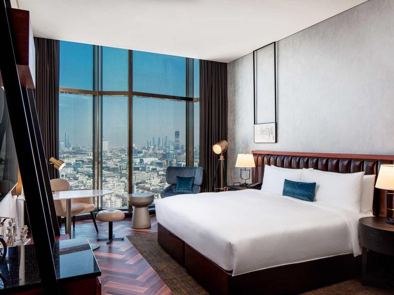 Modern hotel room with large bed and panoramic city view.