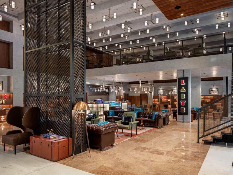 Modern hotel lobby with seating areas, lighting, and multi-level interior space.