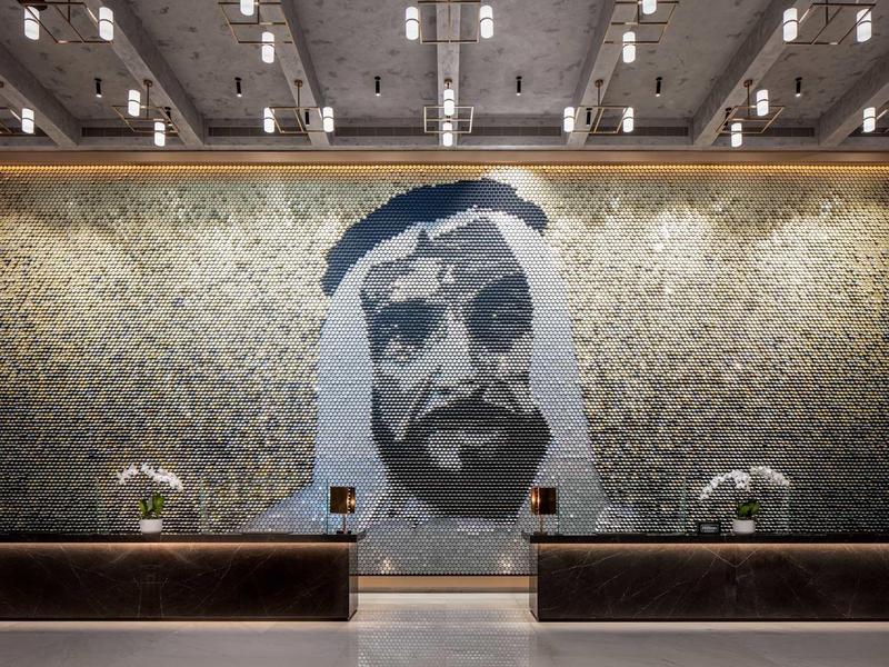 Large wall mosaic of a man in traditional Arab attire in a hotel lobby area.