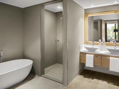 Modernes Badezimmer mit freistehender Badewanne, Doppelwaschbecken und großem Spiegel.