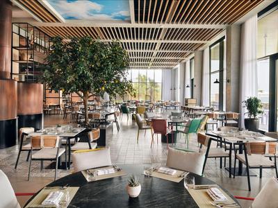 Hell eingerichteter Speisesaal mit Tischen, Stühlen und großen Fenstern in einem Hotel.