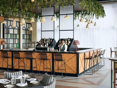 Moderner Barbereich mit Holzfront, schwarzen Barhockern und grünen hängenden Pflanzen.