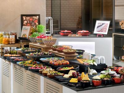 Ein Buffet mit verschiedenen Speisen, Salaten, Früchten und Desserts auf schwarzen Tabletts.