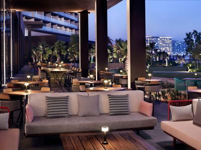 Moderne Hotelterrasse mit Sitzgruppen und Blick auf Stadtbeleuchtung bei Dämmerung.