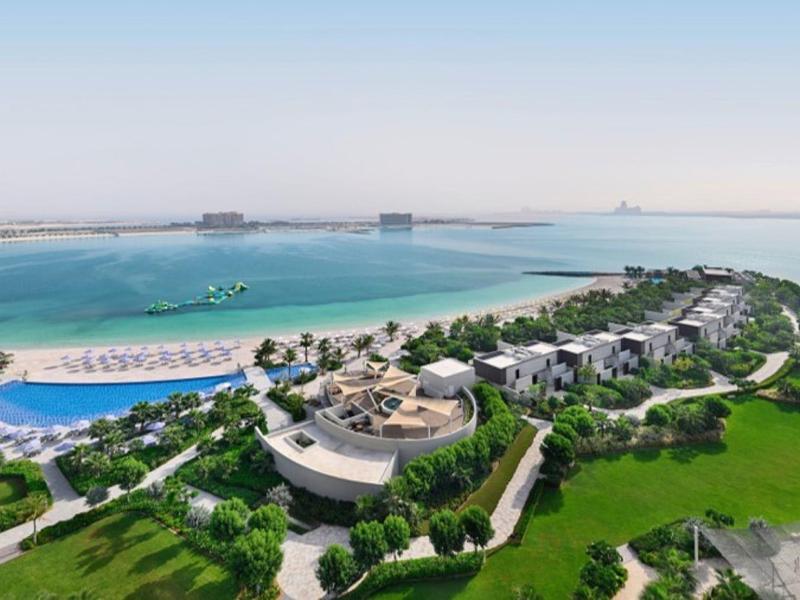 Luxuriöse Resortanlage am Meer mit großem Pool, Palmen und weitläufigen Grünflächen.