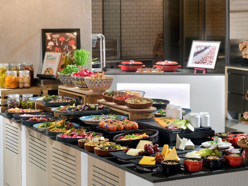 Ein Buffet mit verschiedenen Speisen, Salaten, Früchten und Desserts auf schwarzen Tabletts.