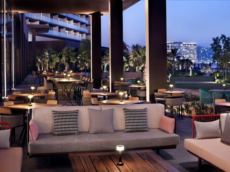 Moderne Lounge mit gemütlichen Sofas, Holztischen und stimmungsvoller Beleuchtung bei Abenddämmerung.