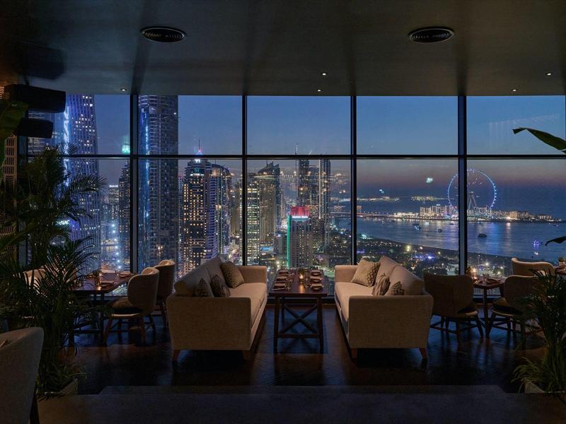 Salon z sofami i widokiem na oświetlone drapacze chmur nocą.