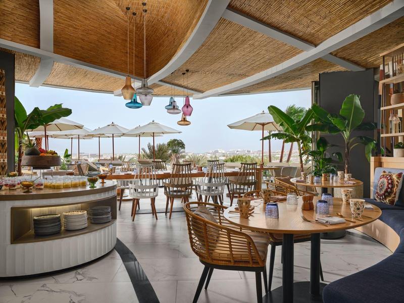 Bright outdoor dining area with wooden chairs, tables, and sun umbrellas.