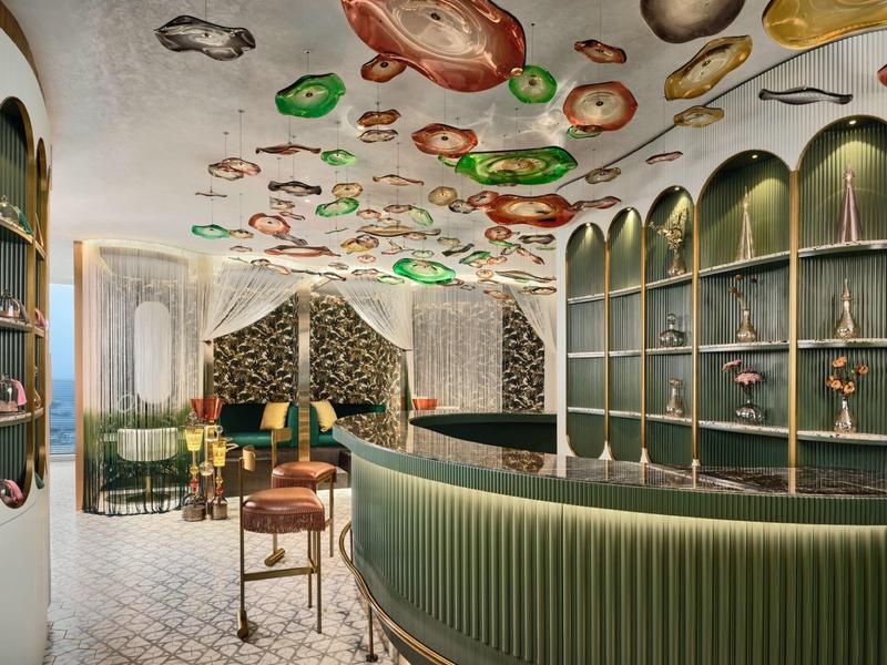 Elegant hotel lounge with green counter, colorful ceiling lights, and stylish furniture.