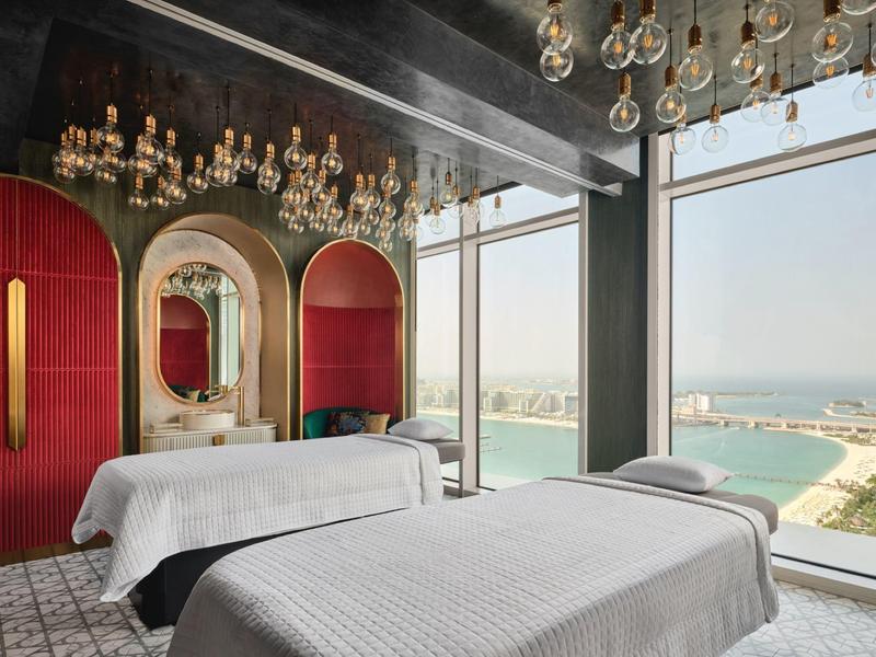 Modern spa with two massage tables and floor-to-ceiling windows overlooking the sea.