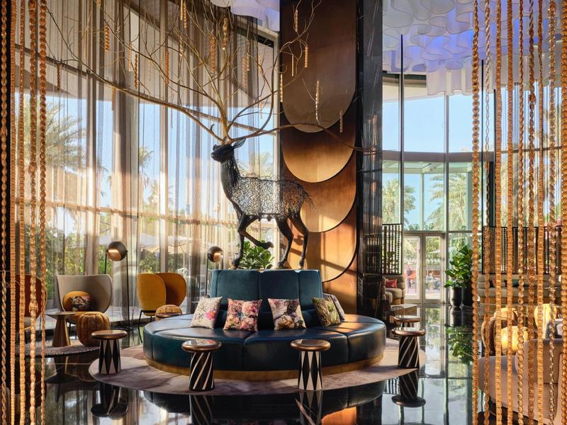 Elegant hotel lounge with round seating areas, large windows, and decorative partitions.