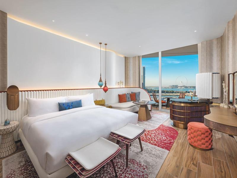 Modern hotel lobby with seating areas, wooden walls, and colorful ceiling lights.