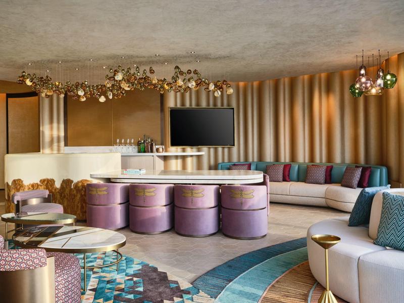 Modern hotel lounge with round seating and large TV screen.