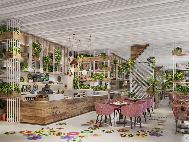 Moderní restaurace s dřevěným nábytkem, zelenými rostlinami a růžovými židlemi v světlém prostoru.