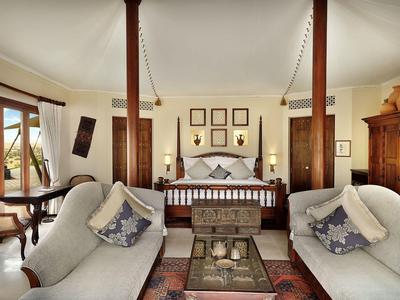 Wohnzimmer mit zwei Sofas, Holzmöbeln und einem großen Bett im Hintergrund.