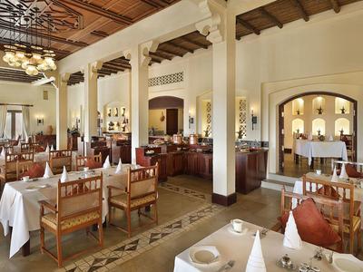 Elegant restaurant with white tablecloths and wooden chairs in bright room with columns.