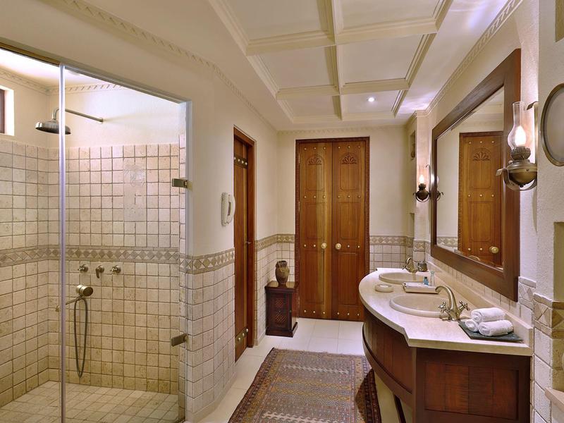 Bright bathroom with shower, sink, and wooden cabinets in warm design.