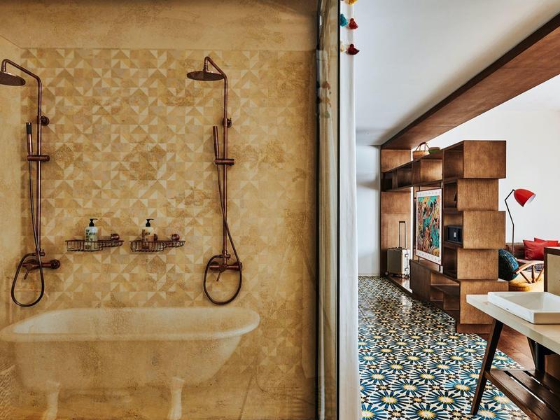 Modernes Bad mit Doppel-Dusche, Mosaikfliesen und angrenzendem Wohnbereich mit buntem Boden.