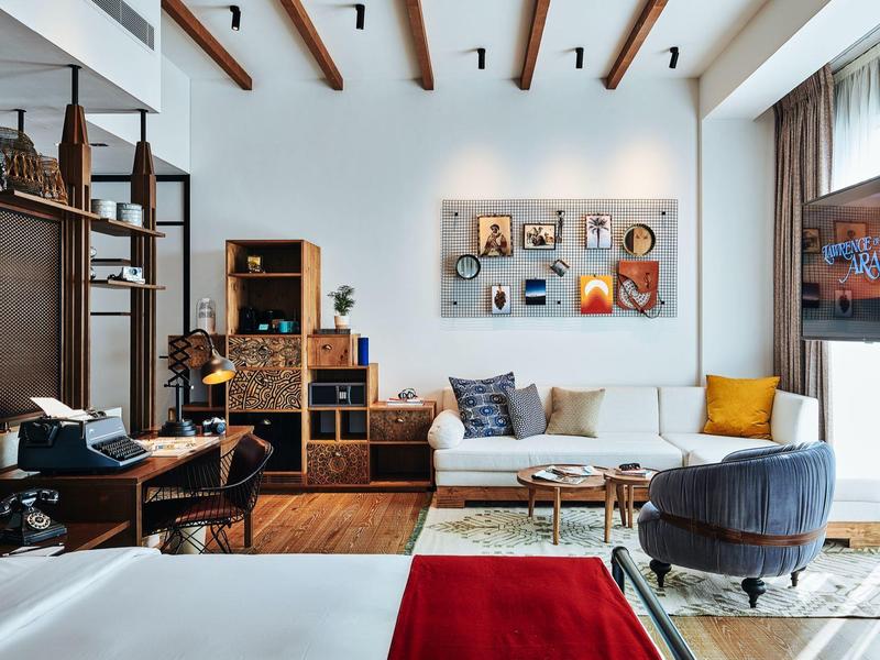 Hell eingerichtetes Wohnzimmer mit Holzdeckenbalken, gemütlichen Sitzmöbeln und moderner Kunst an der Wand.