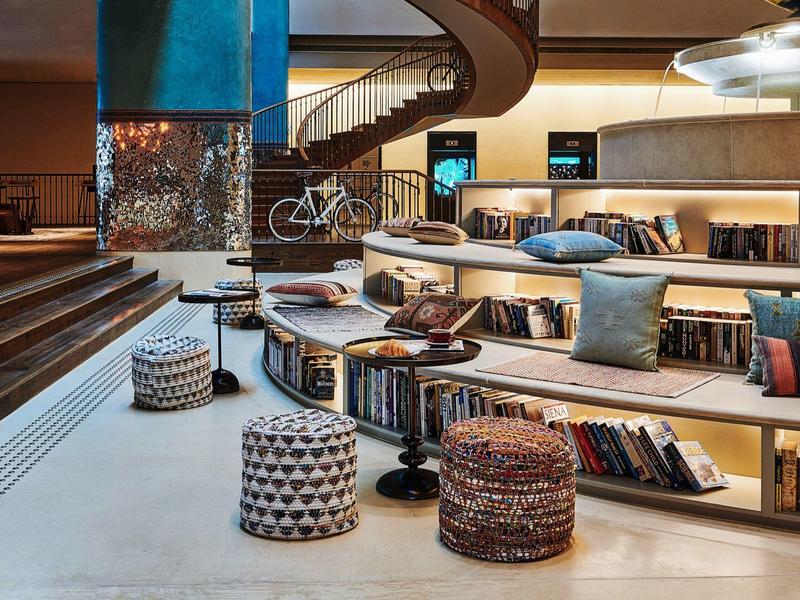 Modernes Wohnzimmer mit runden Bücherregalen, bunten Sitzhockern und gepolsterten Sitzkissen.