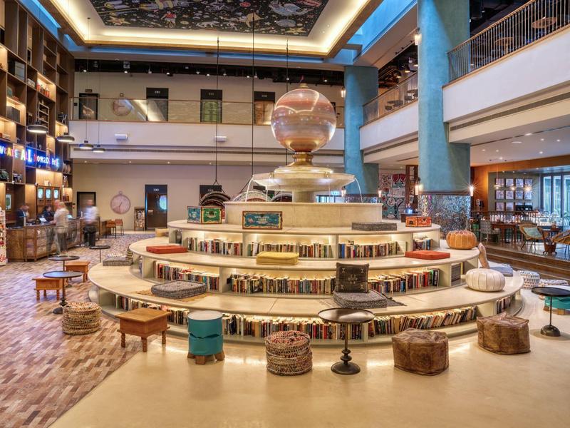 Großer runder Bücherständer mit Sitzecken in einer modernen, mehrstöckigen Bibliothek.