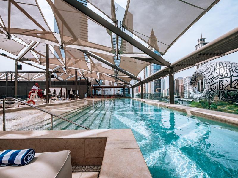 Moderner Außenpool mit breitem Glasdach, Seitendekorationen und bequemen Lounge-Bereichen.