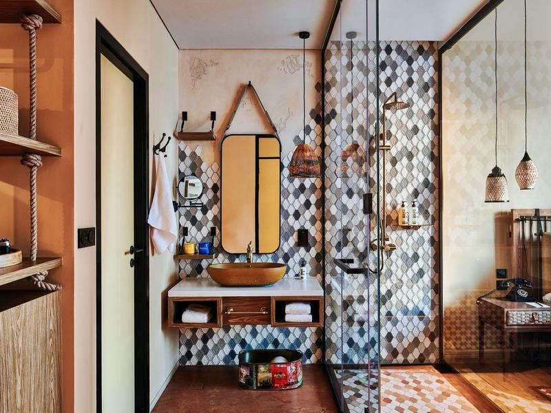 Modernes Badezimmer mit Glasdusche, hölzernem Waschbecken und gemusterten Fliesen an Wand und Boden.