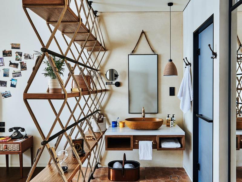 Moderner Waschtisch mit Holzregalen, großer Spiegel, Holztisch und dekorativen Elementen.