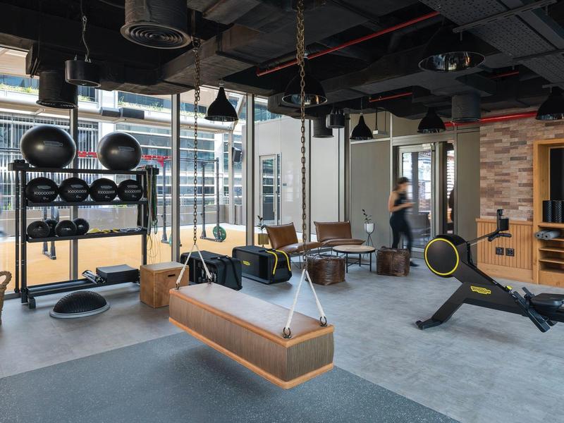 Moderner Fitnessraum mit Rudergerät, Hanteln, Sitzbank und großen Fenstern für Tageslicht.