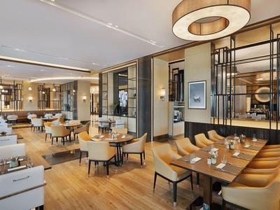 Nowoczesna restauracja z drewnianymi podłogami, wygodnymi miejscami do siedzenia i stylowym oświetleniem.