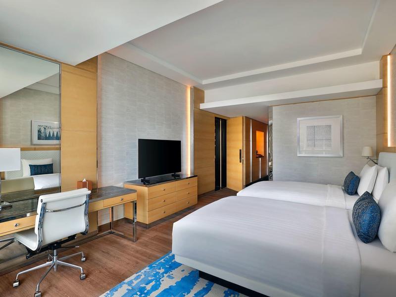 Modern eingerichtetes Hotelzimmer mit großem Bett, Schreibtisch und Fernseher.