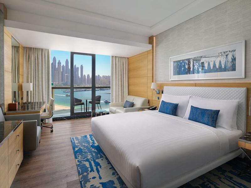 Modernes Hotelzimmer mit großem Bett, Balkon, Stadtblick und gemütlicher, heller Einrichtung.