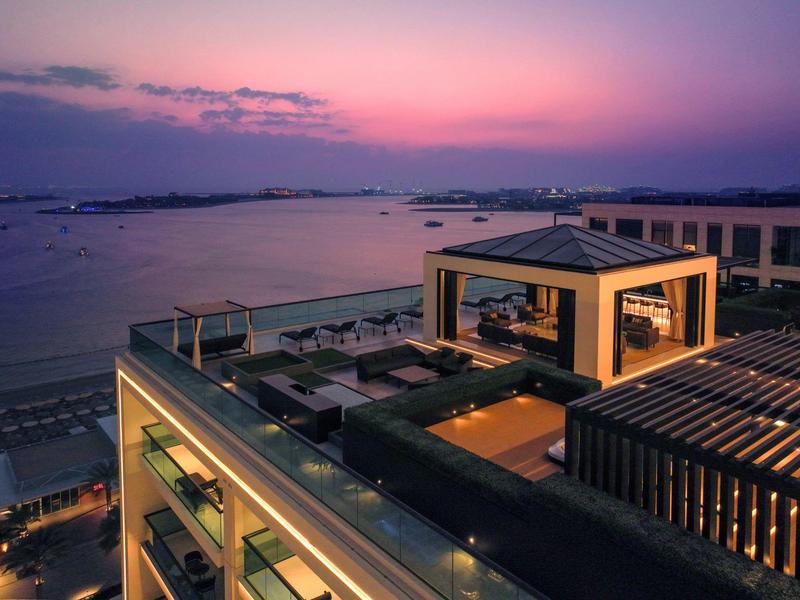 Moderne Dachterrasse mit Sitzplätzen und Grillbereich bei Sonnenuntergang am Meer, ruhige Atmosphäre.