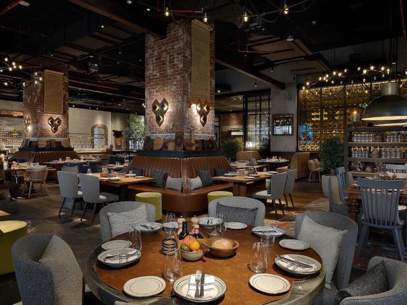 Gemütliches Restaurant mit runden Tischen, gedeckten Plätzen und warmem Holz- und Steinambiente.