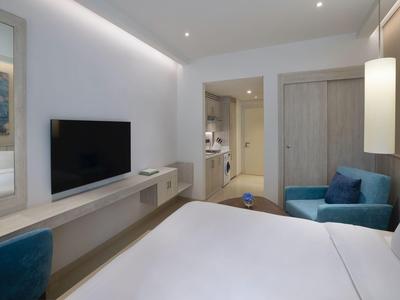 Basen infinity z leżakami z widokiem na miasto nad wodą pod czystym niebem.