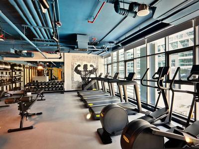Modern gym with treadmills, dumbbells, and large windows overlooking the city.