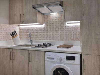 Moderne kleine Küche mit Holzschränken, Spüle, Gasherd, Waschmaschine und Messerblock.