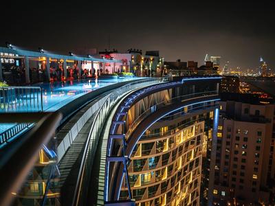 Moderne Hochhausfassade mit bunten Lichtern und glattem Geländer bei Nacht in der Stadt.