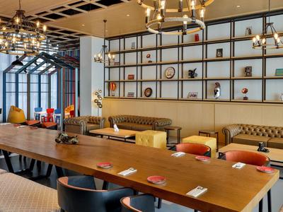 Moderner Essbereich mit langem Holztisch, gepolsterten Stühlen und großer Wandregal-Dekoration.