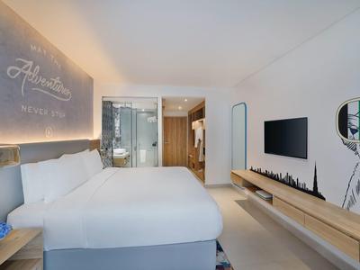 Modernes Hotelzimmer mit großem Bett, Glasbad, weißem Design und Wandgrafik im Raum.