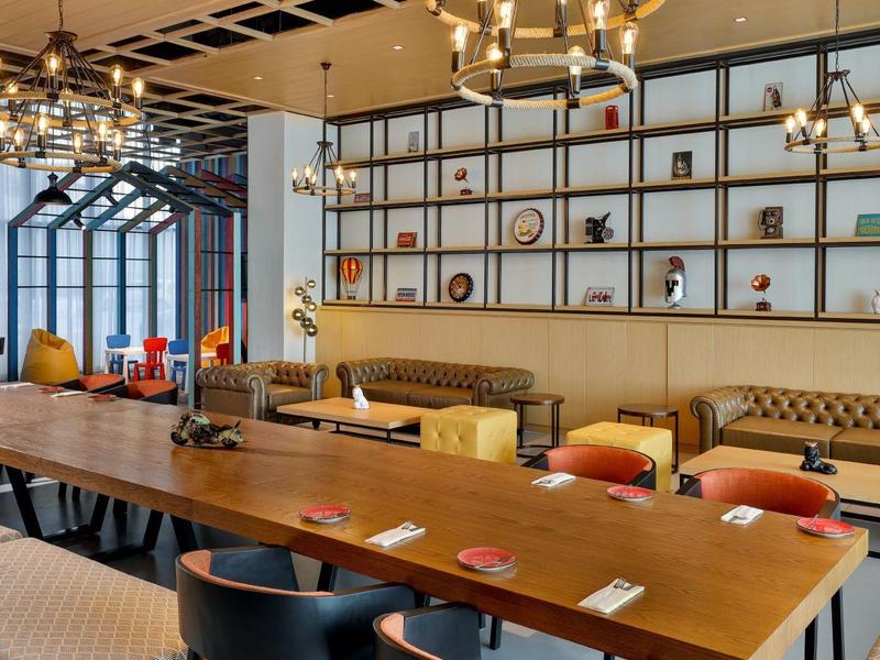 Moderner Essbereich mit langem Holztisch, gepolsterten Stühlen und großer Wandregal-Dekoration.