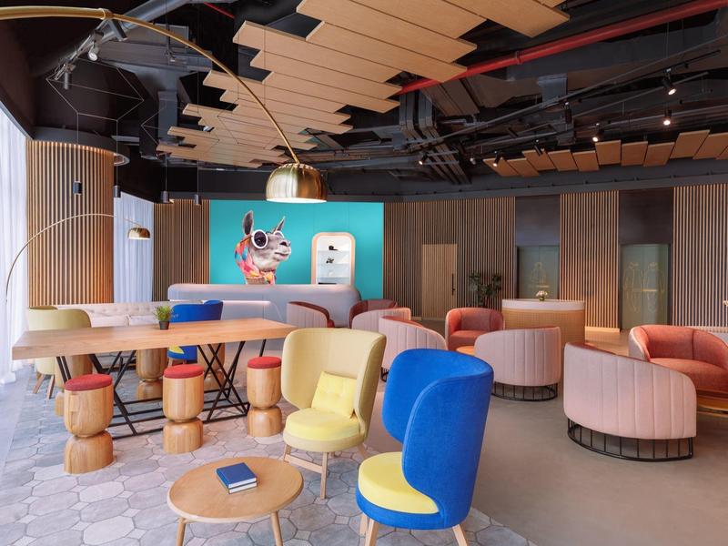 Modernes, buntes Wartezimmer mit weichen Sesseln, Holztischen und stilvoller Deckenbeleuchtung.