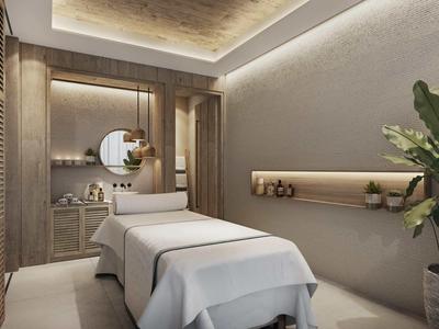 Moderner Behandlungsraum mit zwei Liegen, warmem Licht, Pflanzen und eleganter Wanddekoration.