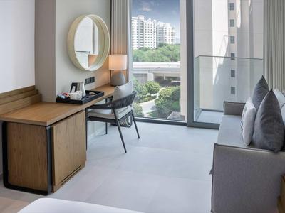 Modernes Zimmer mit Schreibtisch, Stuhl, Sofa und großem Fenster mit Stadtblick.