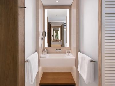 Enge Badezimmer mit weißen Wänden, Handtüchern an beiden Seiten und mehreren Spiegeln.