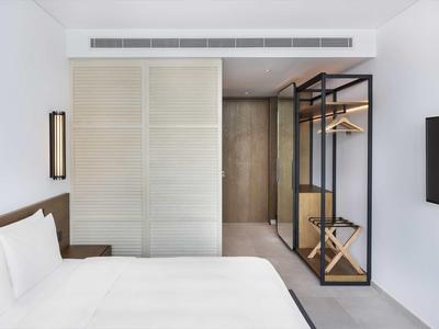 Modernes, minimalistisches Schlafzimmer mit weißem Bett, Schiebetür und offenem Kleiderschrank aus Metall.