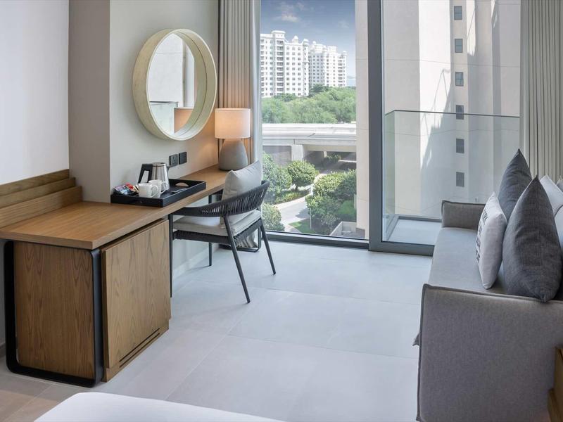 Modernes Zimmer mit Schreibtisch, Stuhl, Sofa und großem Fenster mit Stadtblick.